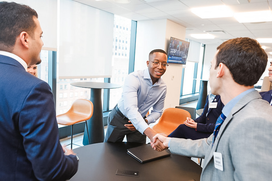 two people leaning over a round table to shake hands